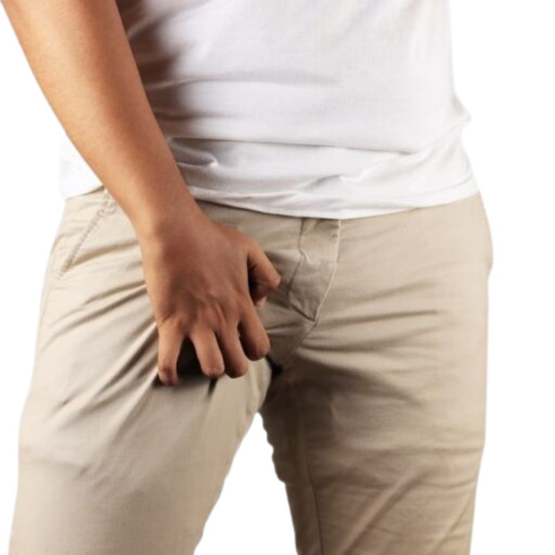 A person in a white shirt and beige pants appears to be adjusting the front pocket area, possibly contemplating jock itch treatment for relief.