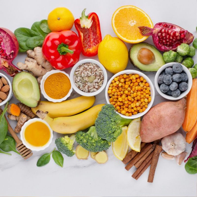 A variety of colorful fruits, vegetables, and spices arranged on a white background. These foods form the basis of an anti-candida cleanse diet.