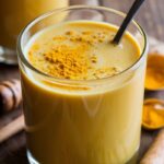 Single glass of candida-friendly golden milk latte, dairy-free and sugar-free, topped with a sprinkle of turmeric on top