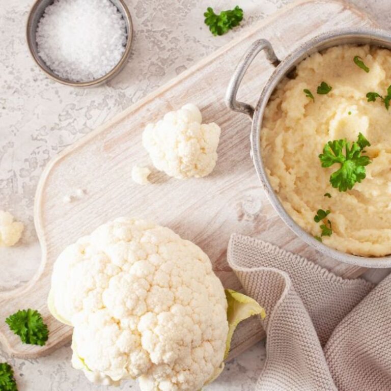 bowl of herbed cauliflower mash and cauliflower head on bench