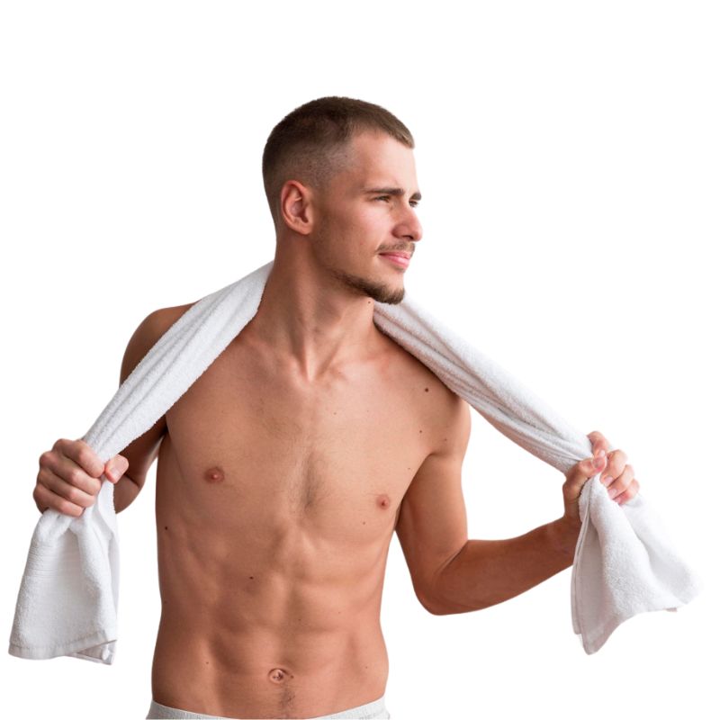 A man with short hair stands shirtless against a white background, holding a towel around his shoulders and looking to the side, pondering if jock itch is contagious.