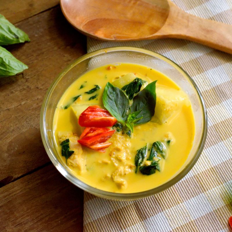high angle view of a coconut lemongrass curry in a glass bowl resting on a teatowel