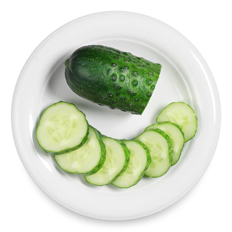 a white plate with a cucumber and half of it sliced - cucumber slices with almond butter for candida diet