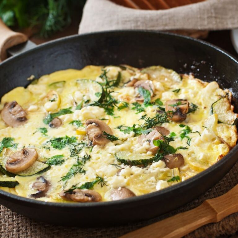 scrambled eggs with zucchini and herbs in a cast iron frying pan