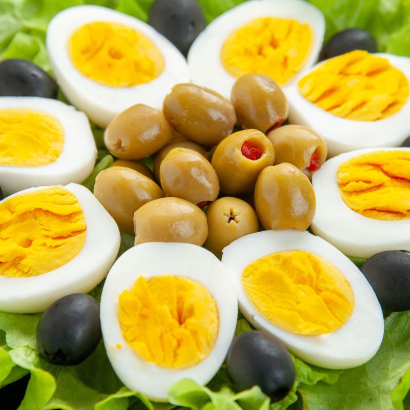 halved hard boiled eggs and olives set on a bed of lettuce leaves