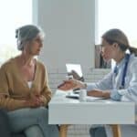 A doctor consults with a patient in an office, pointing to a document on the desk, discussing treatment options for vaginal yeast infection.