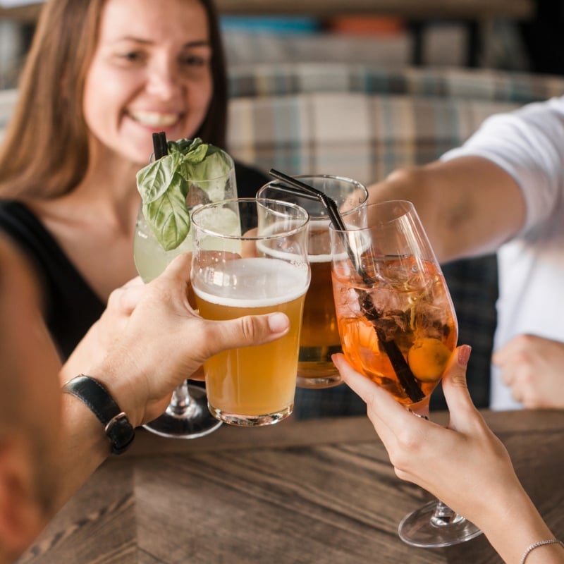 Group of friends toasting with various drinks at a social gathering.