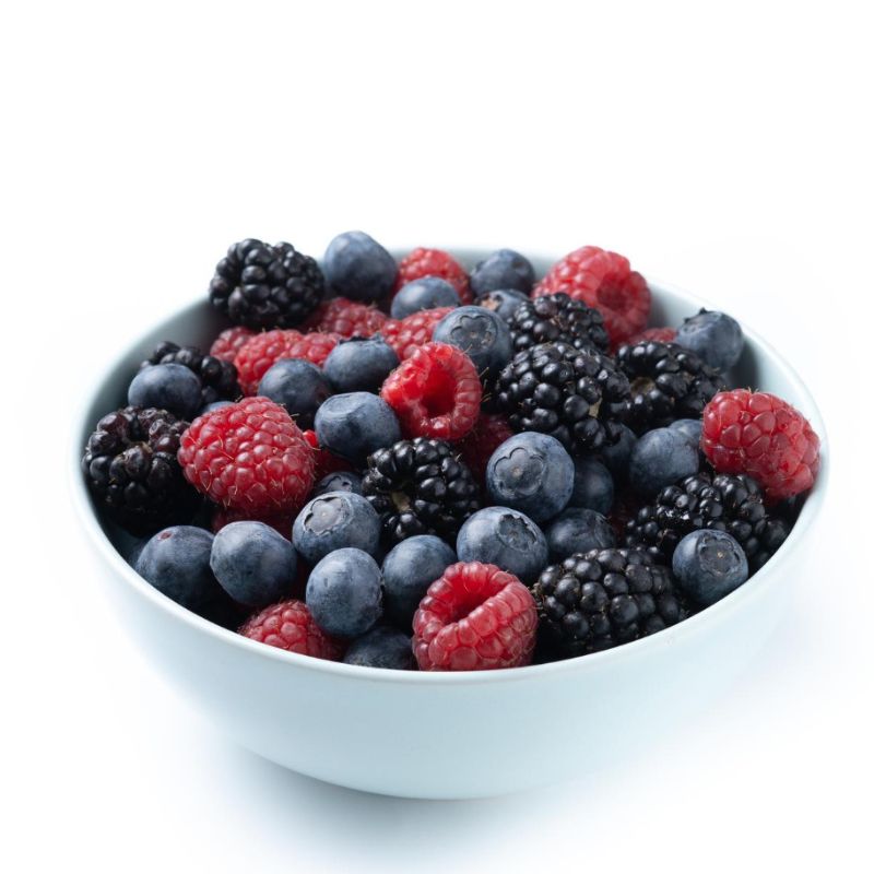 A white bowl filled with fresh blueberries, raspberries, and blackberries against a white background, perfect for those who have undergone food intolerance testing to ensure they can enjoy these delicious berries safely.