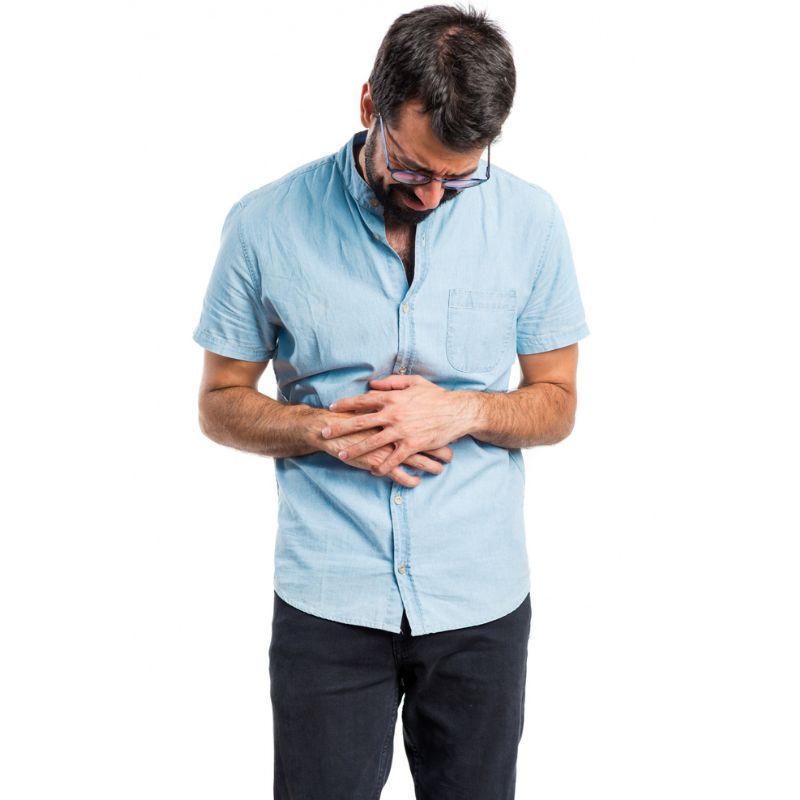 Man in blue shirt experiencing stomach pain in need of a candida cleansing diet.