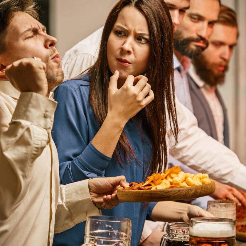 Group of friends with varied reactions to a plate of snacks at a gathering.